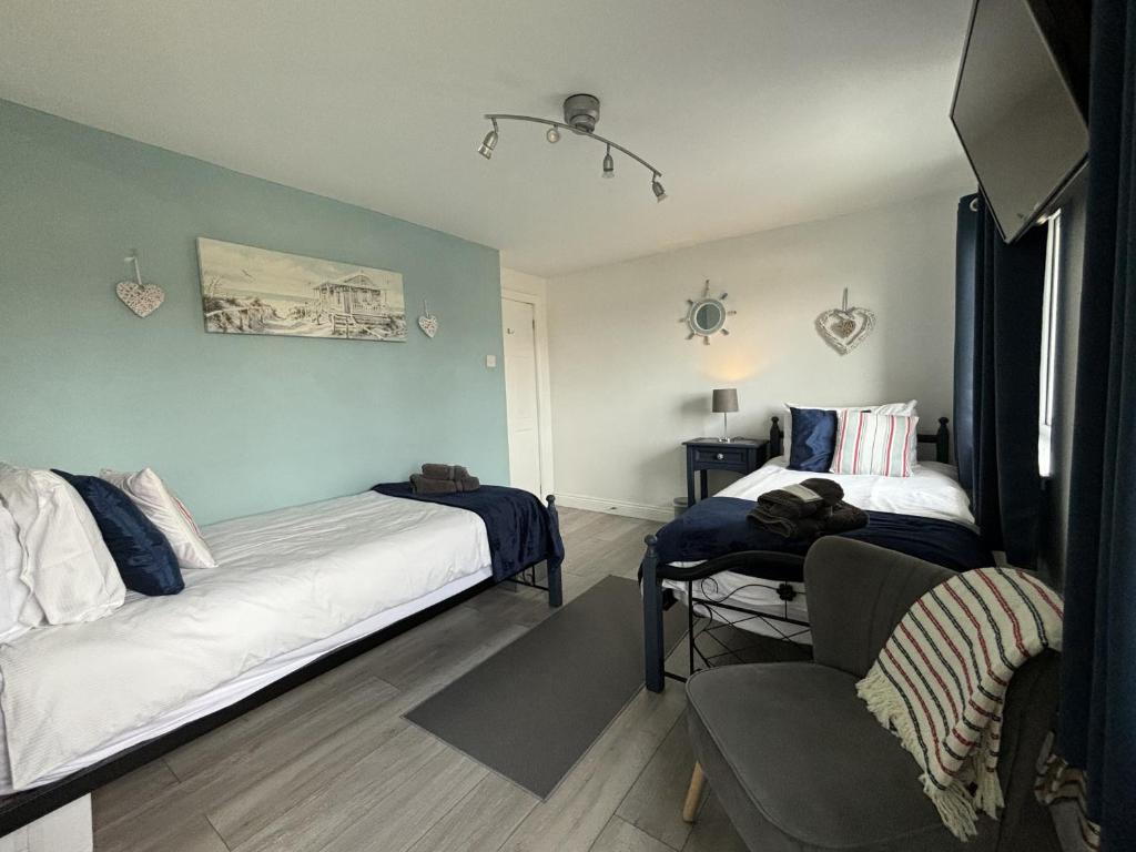 a bedroom with two beds and a chair in it at Craster Crew House in Craster