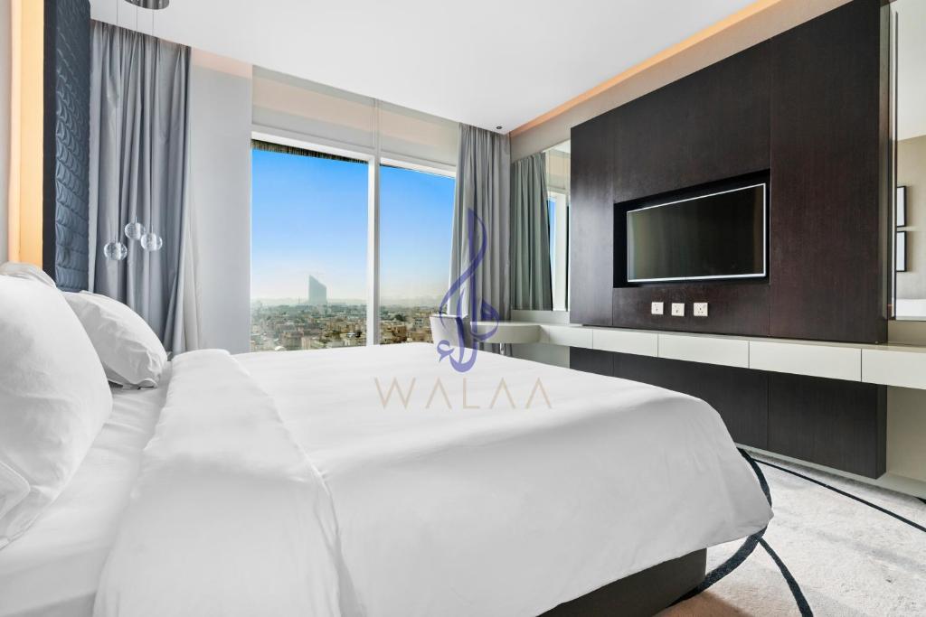 1 dormitorio con 1 cama blanca y TV en Walaa Homes Elite Studio at Damac Esclusiva Tower Riyadh-401, en Riad