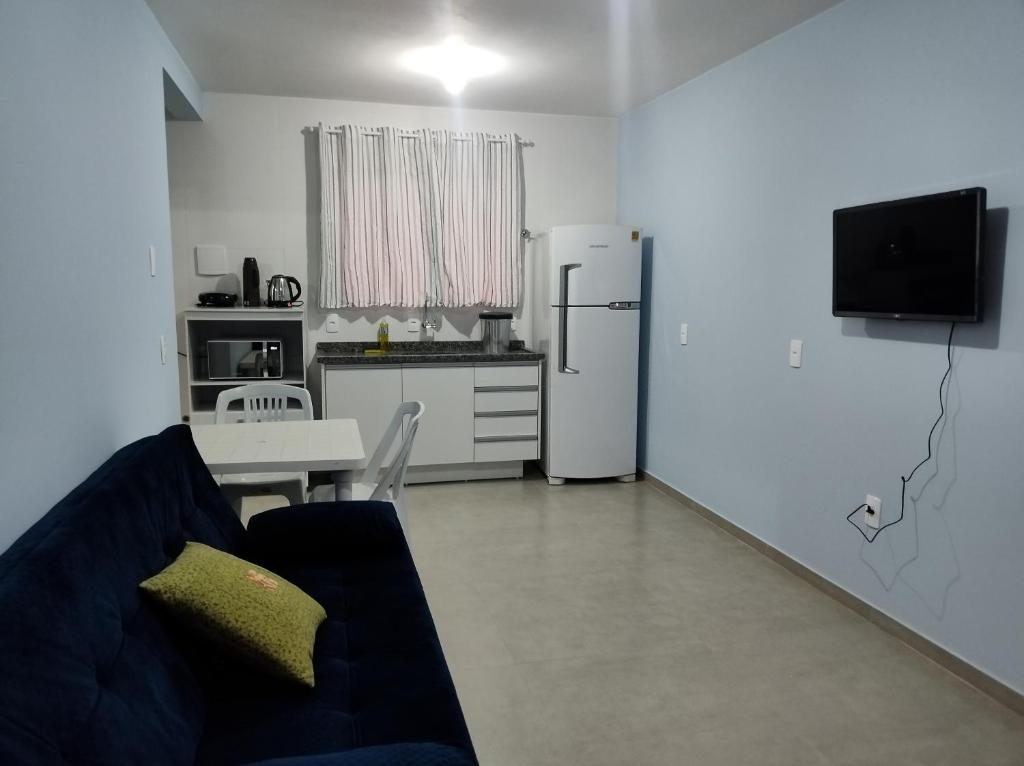 ein Wohnzimmer mit einem Sofa und eine Küche mit einem Kühlschrank in der Unterkunft Hotel Morro do campo in Antônio Carlos