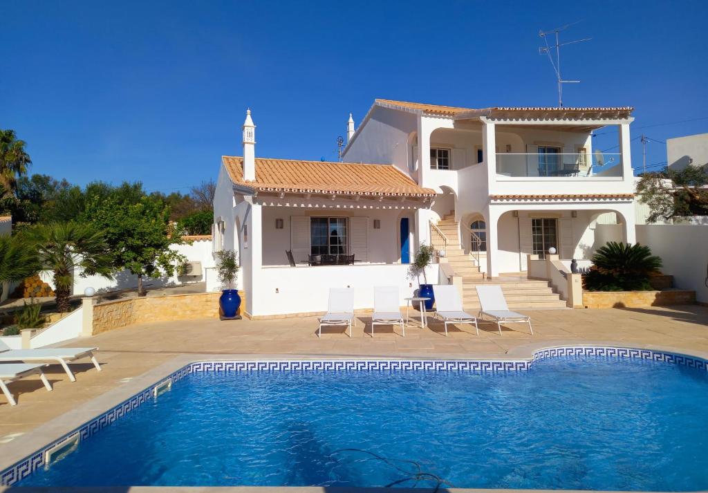 a villa with a swimming pool in front of a house at Villa with pool and sea view with two independent floors in Faro