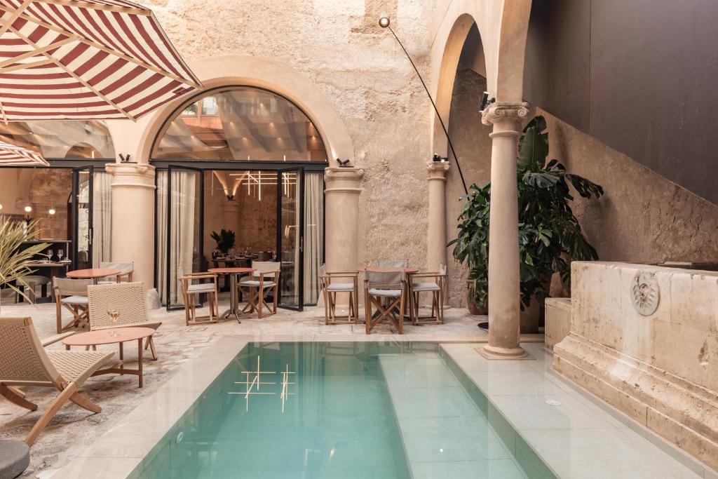 een zwembad in een gebouw met stoelen en tafels bij Nobis Hotel Palma, a Member of Design Hotels in Palma de Mallorca