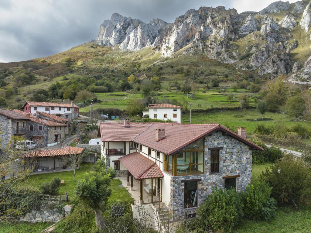 uma casa numa aldeia em frente a uma montanha em Posada Cabañes em Cabañes