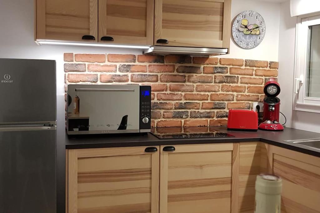 a kitchen with a microwave and a brick wall at Le Patio in Saintes-Maries-de-la-Mer