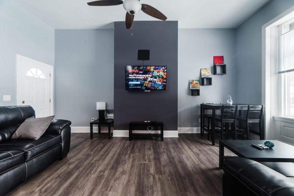 a living room with a black couch and a ceiling fan at Massive Home - GroupStay - Parking & Location in Pittsburgh