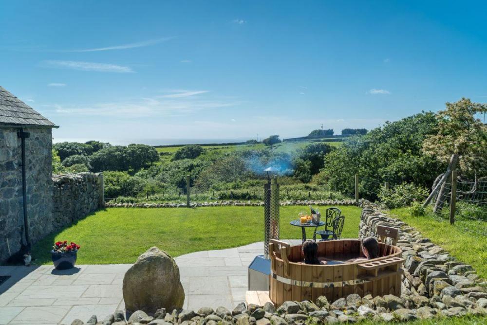 a garden with a hot tub and a stone wall at Melin-Byrdir in Dyffryn