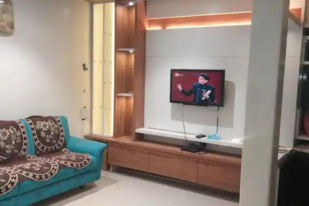 uma sala de estar com um sofá azul e uma televisão em Luxurious 2BHK bunglow with garden em Sholapur