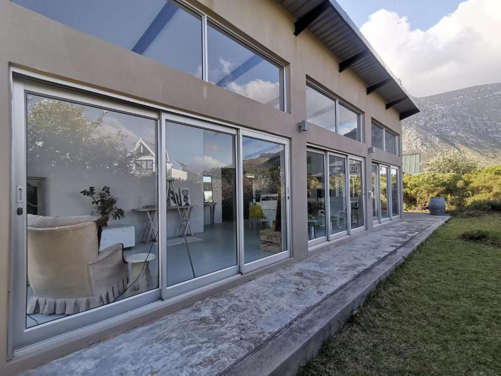 ein Haus mit Glasfenstern und einer Terrasse in der Unterkunft Betty's Bay Cottage in Bettyʼs Bay