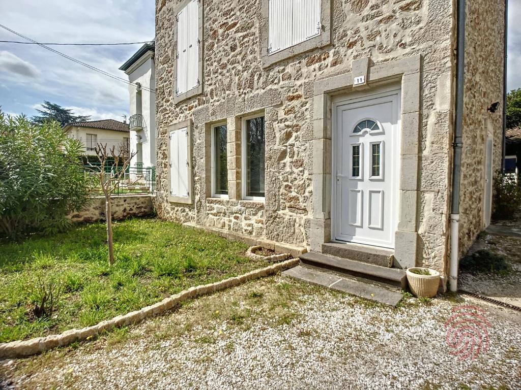 una casa de piedra con una puerta blanca y un patio en Maison Lamalou-les-Bains, 4 pièces, 6 personnes - FR-1-451-45, en Lamalou-les-Bains
