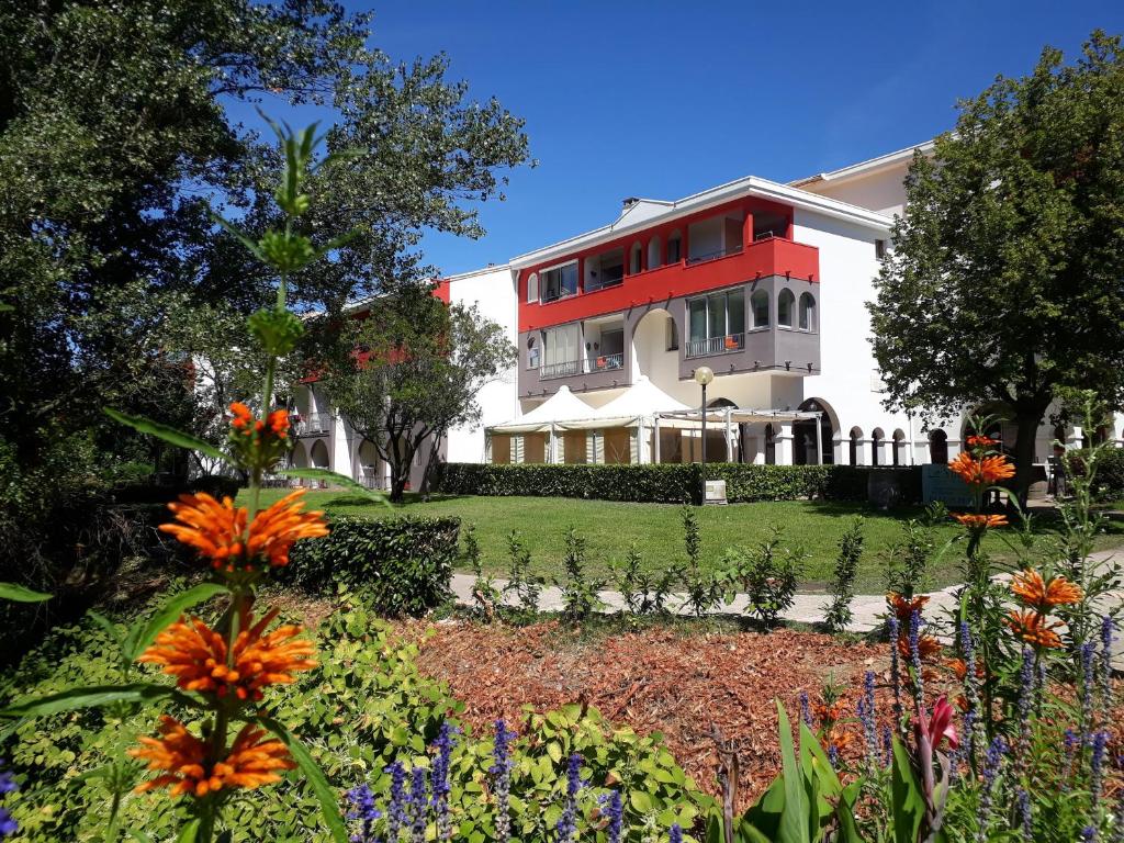une maison rouge et blanche avec un jardin et des fleurs dans l'établissement Appartement Lamalou-les-Bains, 2 pièces, 2 personnes - FR-1-451-107, à Lamalou-les-Bains