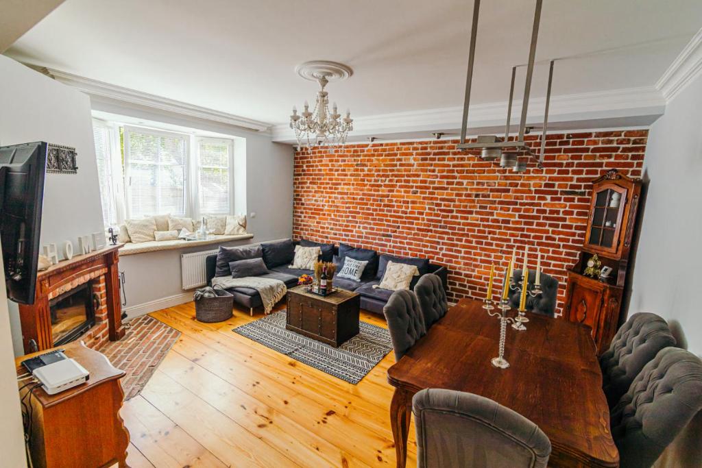 a living room with a brick wall and a table at Apartamenty Colobrzeg Sweet Home in Kołobrzeg
