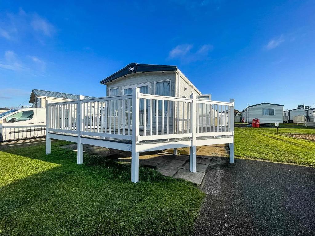 ein großes weißes Haus mit einer großen Veranda in der Unterkunft Spacious Caravan With Large Decking Area, Perfect To Enjoy The Sun, Ref 23058c in Hunstanton