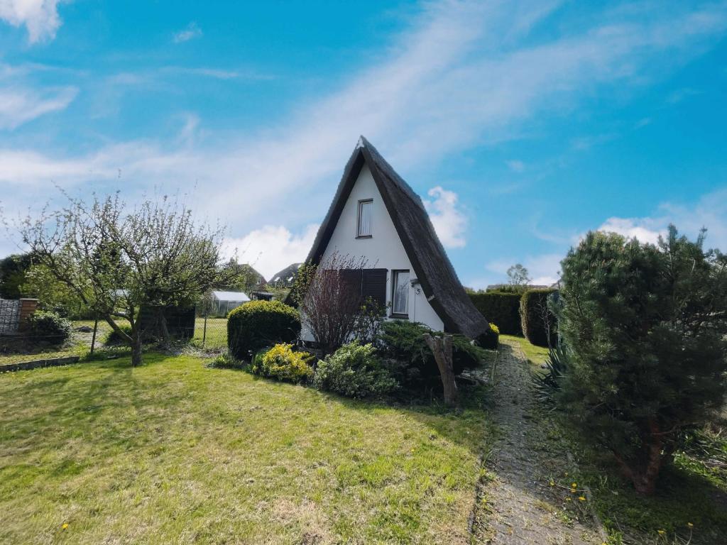 a small white house with a pointed roof at Finnhütte nah am Strand 