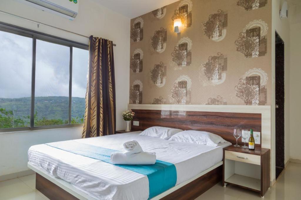 a bedroom with a large bed and a large window at Hill View Bungalow,Mahabaleshwar With Private Swimming Pool in Mahabaleshwar