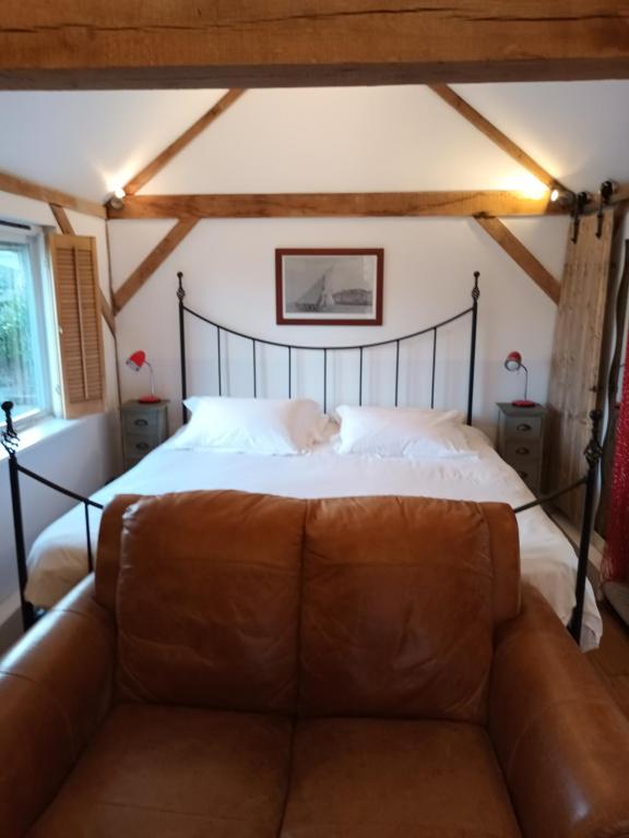 a bedroom with a bed with a leather couch at The Music Room - Kingsize Double - Sleeps 2 - Quirky - Rural in Haslemere