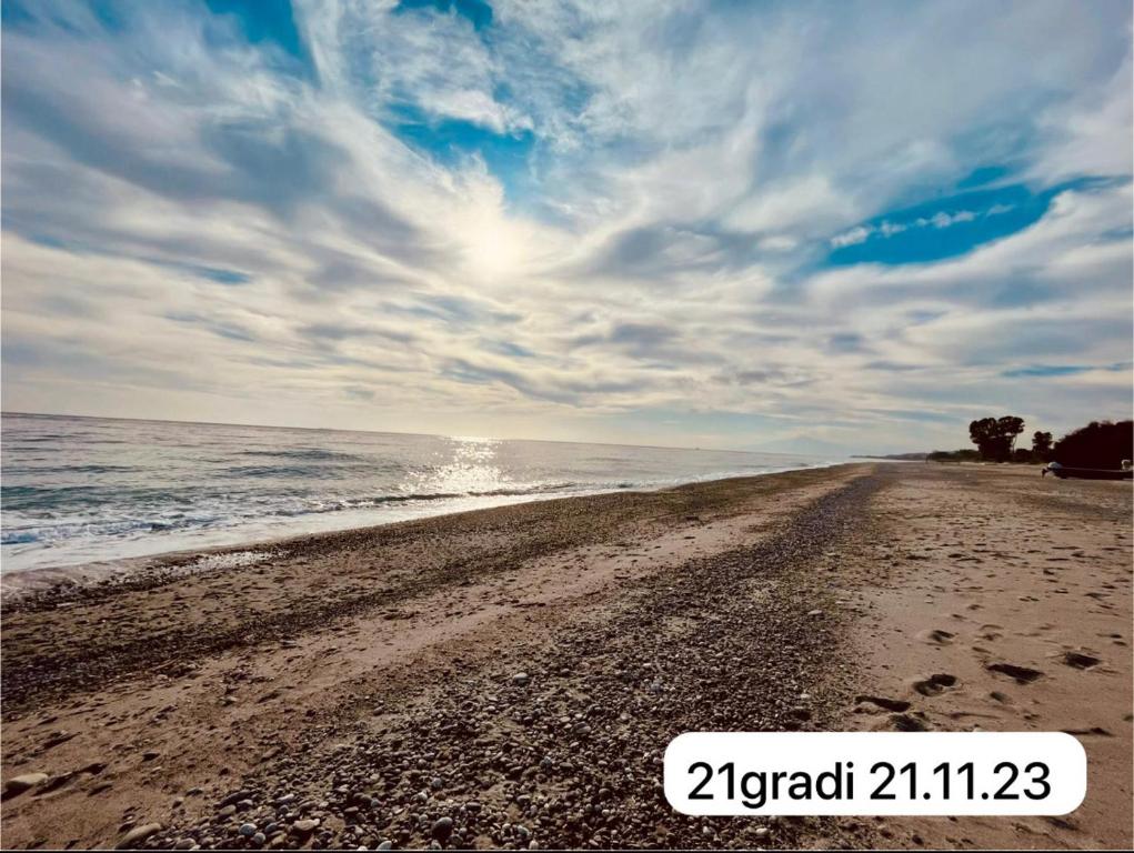 a sandy beach with the ocean on a cloudy day at The Greek’ House in Bova Marina