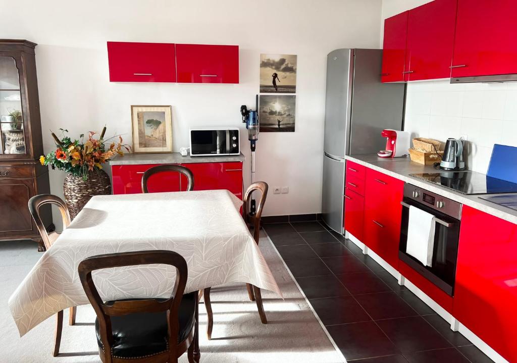 une cuisine avec des placards rouges et une table avec des chaises dans l'établissement L'Ecrin - Charmant logement entre Paris & Disney, à Champigny-sur-Marne