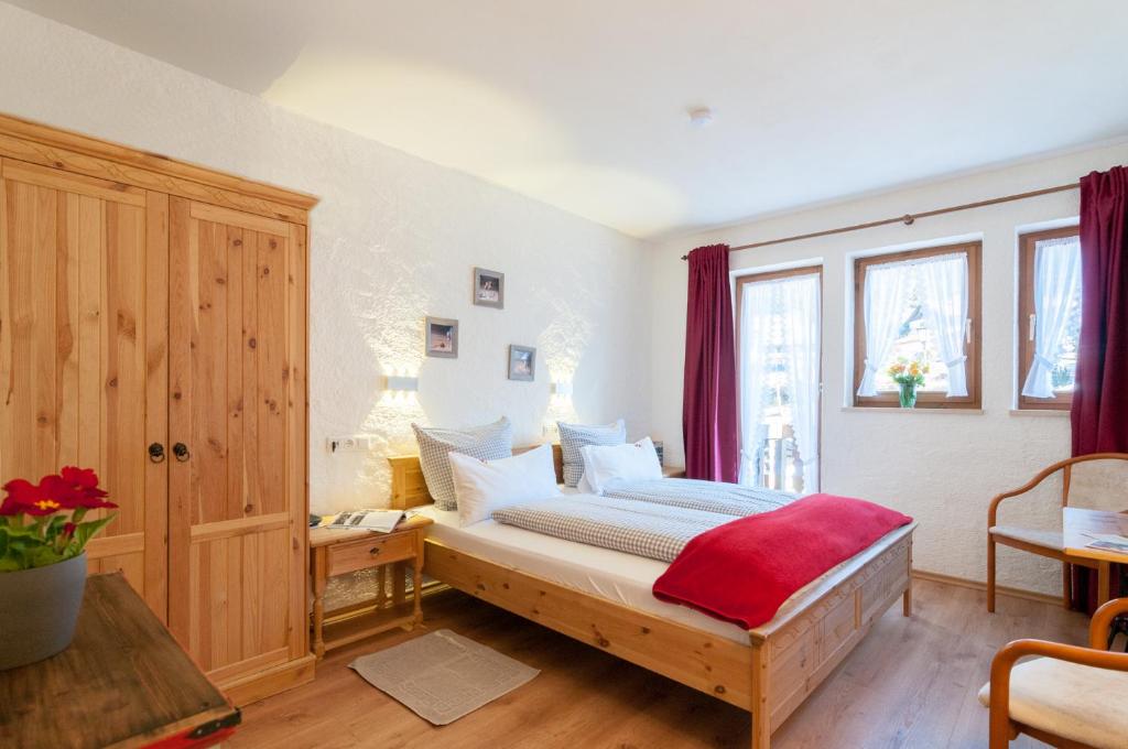 a bedroom with a bed with a red blanket on it at Hotel Garni Effland in Bayrischzell