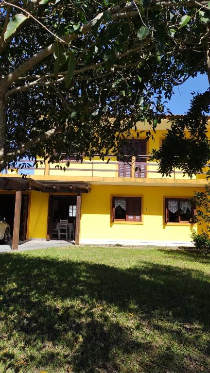 una casa amarilla con césped delante en Casa de praia para família - 3 quartos - acomoda até 10 pessoas en Tramandaí