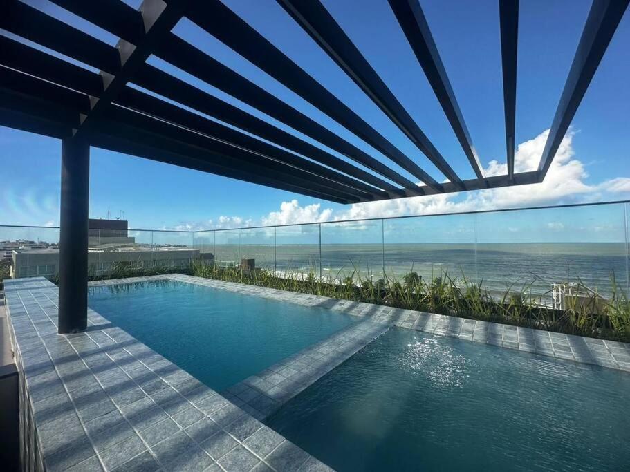 a swimming pool with a view of the ocean at Excelente Flat beira-mar in Cabedelo
