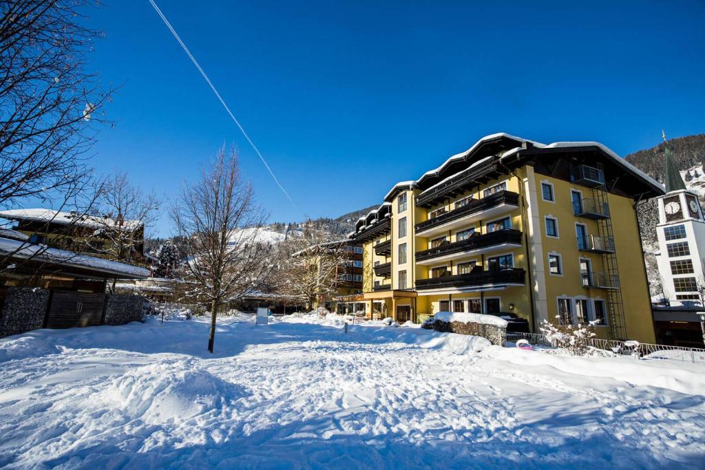 a snow covered yard with a building in the background at Hotel Pinzgauerhof by Alpeffect Hotels in Zell am See