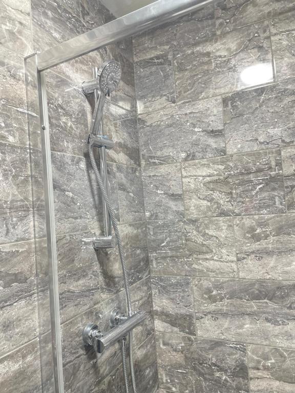 a shower in a bathroom with a stone wall at Retro 3 bed, 2 En-suite Haven in Birmingham