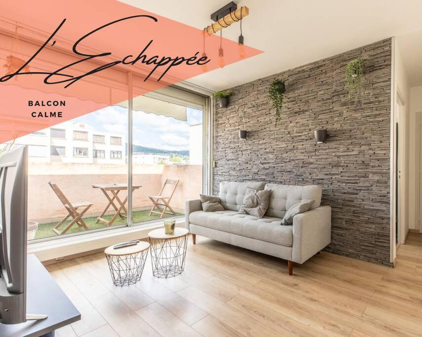 un salon avec un canapé et un mur de briques dans l'établissement *L'Echappée* Balcon & Central, à Chamalières