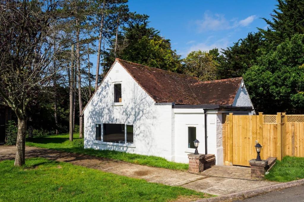 a small white house with a wooden fence at The White Cottage at Gildridge + Private Hot Tub+EV in Chiddingly