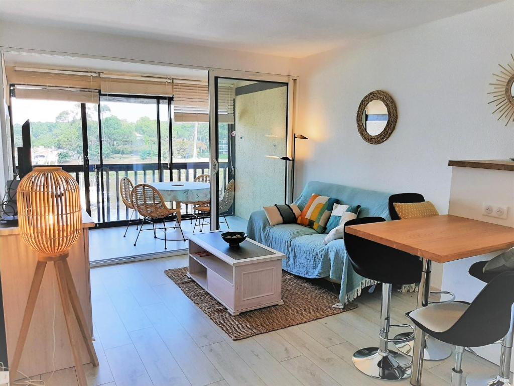 un salon avec un canapé bleu et une table dans l'établissement Bel Appartement Moderne à Capbreton avec Wifi et Parking Privé - FR-1-239-803, à Capbreton