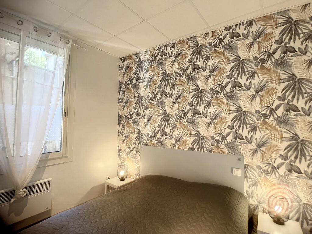 sypialnia z łóżkiem i tapetą w kwiaty w obiekcie Appartement F3 avec Terrasse, Proche Centre et Thermes, Animaux Acceptés - Lamalou-les-Bains - FR-1-451-174 w mieście Lamalou-les-Bains