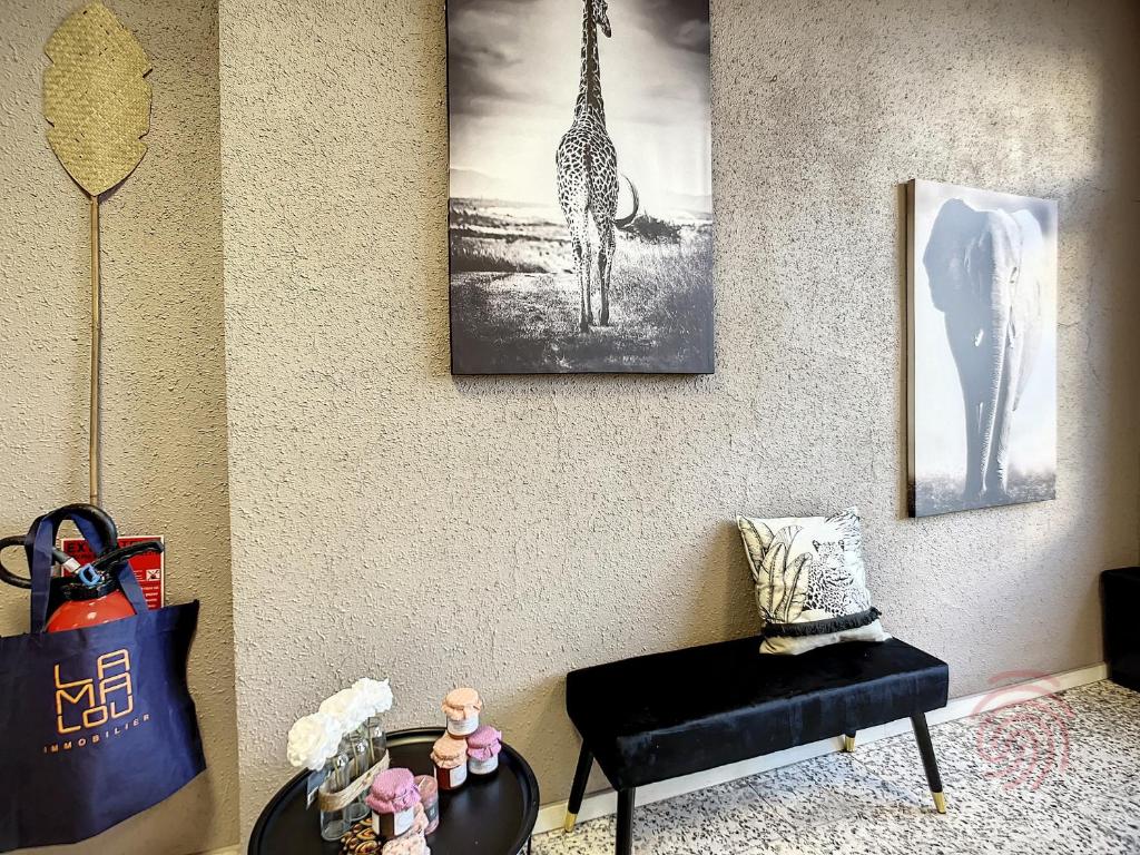 - un salon avec une photo de girafe sur le mur dans l'établissement Charmant Studio en Centre-Ville, Proche Thermes avec Balcons et Wifi – Animaux Acceptés - FR-1-451-177, à Lamalou-les-Bains