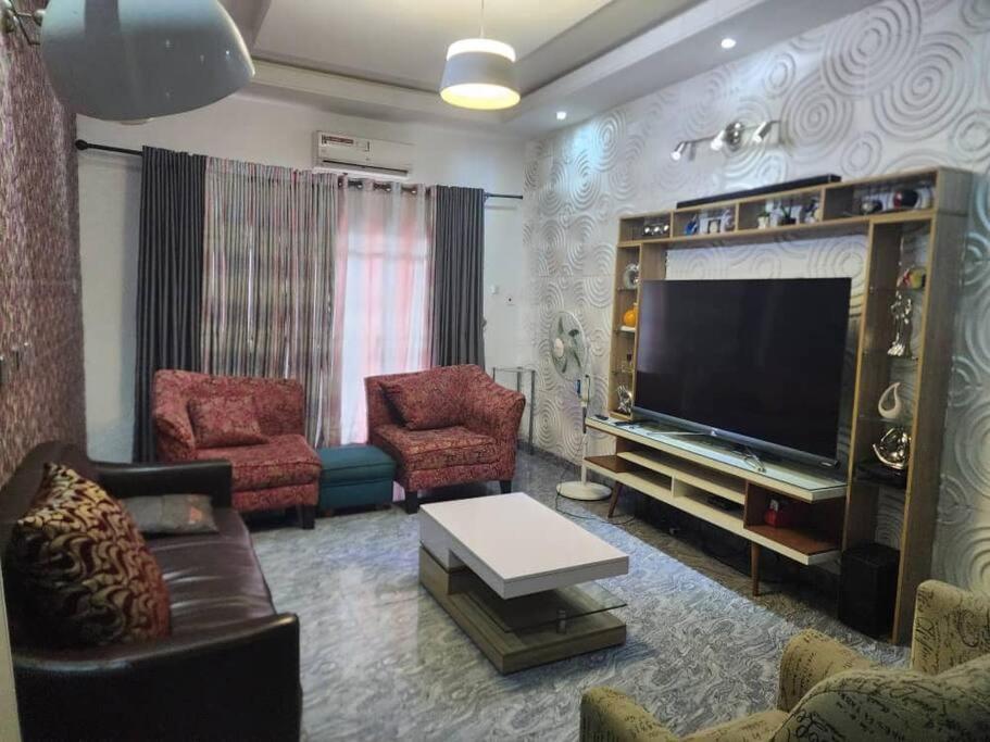 un soggiorno con TV a schermo piatto e sedie di Tastefully furnished apartment a Port Harcourt