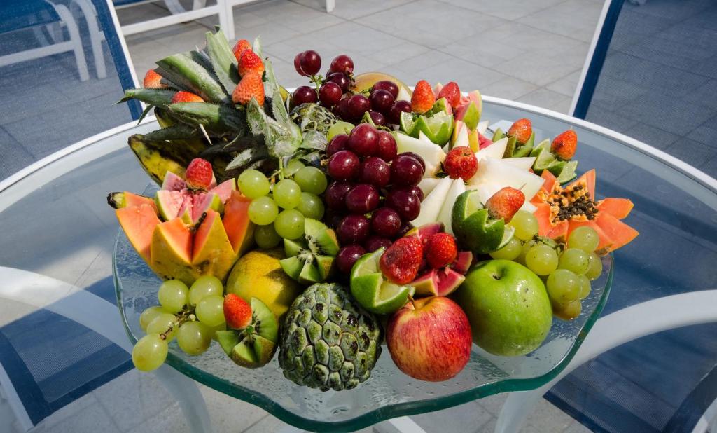 a plate of fruits and vegetables on a glass table at Hotel Jangadeiro in Recife