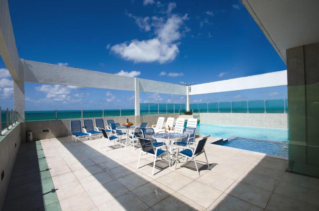 een patio met een tafel en stoelen naast een zwembad bij Hotel Jangadeiro in Recife