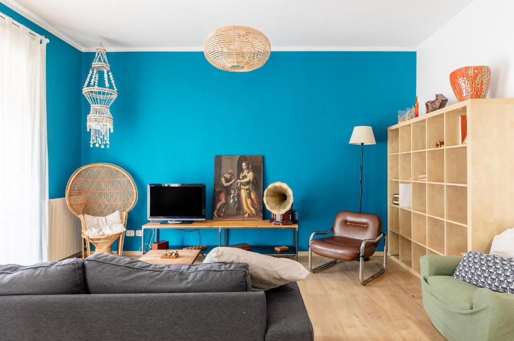 een woonkamer met een bank en een blauwe muur bij Bell’occhio Colorful Apartment with parking in Perugia
