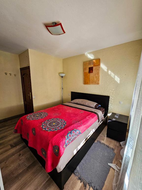 1 dormitorio con 1 cama grande con manta roja en Habitación en Madrid Capital piso compartido en Madrid