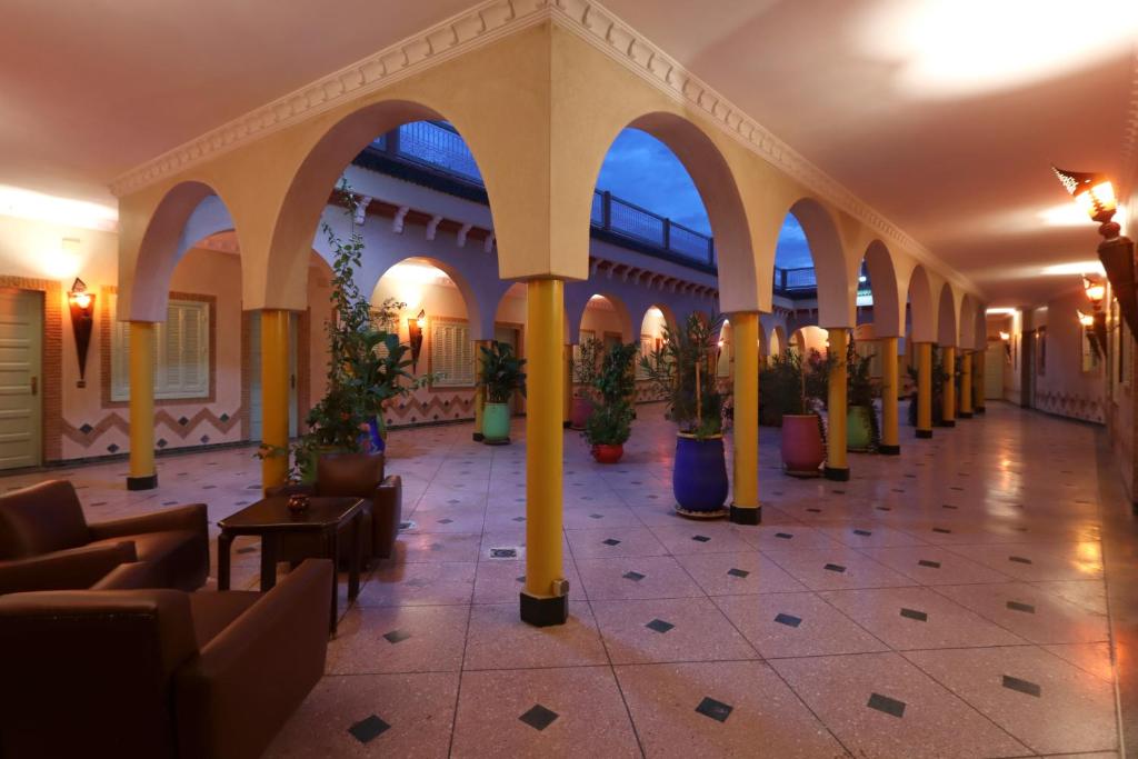 un vestíbulo con columnas, sillas y macetas en HOTEL CTM, en Marrakech