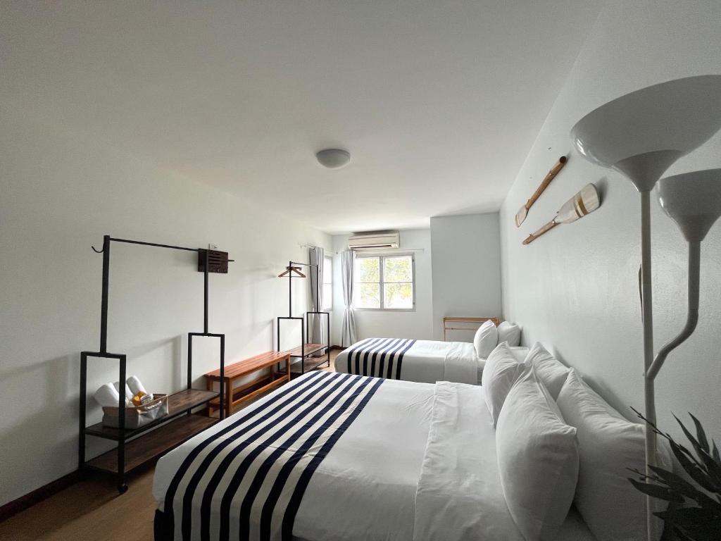 a white bedroom with two beds and a lamp at Nautical Home B&B Khaolak in Khao Lak