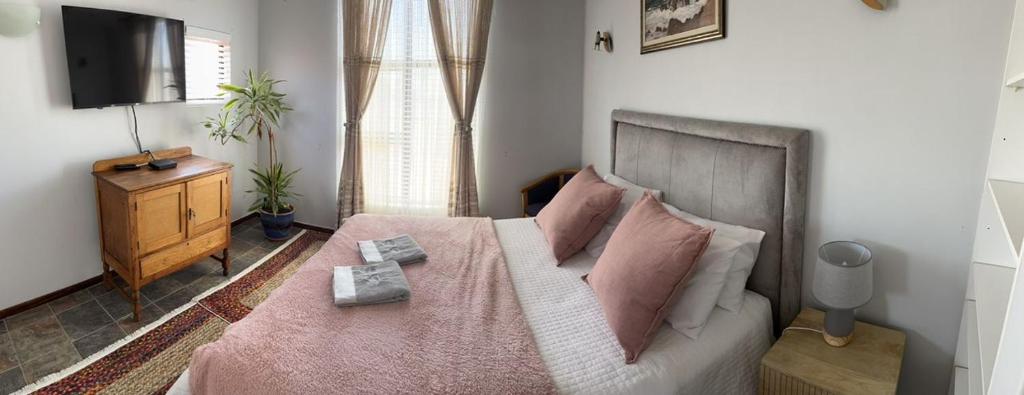 een slaapkamer met een bed met roze kussens en een televisie bij Peaceful Perch in Walvis Bay