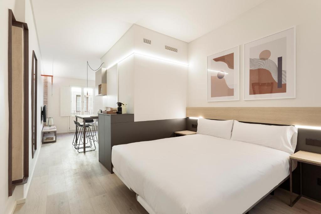 a bedroom with a large white bed and a kitchen at Bcn Town Apartments Born in Barcelona