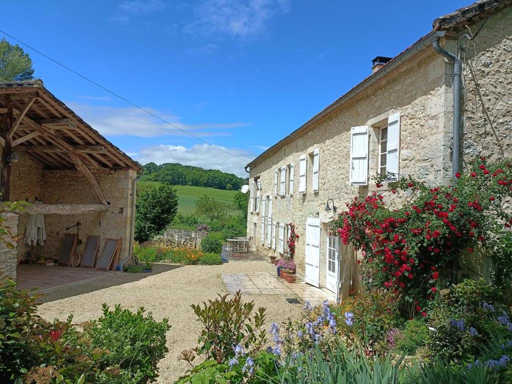 a stone house with flowers on the side of it at Le Moulin de L'Isle - Maison chaleureuse in LʼIsle-Bouzon