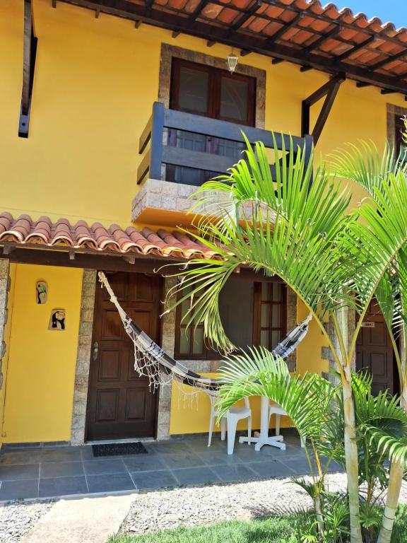 a yellow house with a palm tree in front of it at Uma PAUSA na sua vida, com: sol, praia e sossego! in Cabo Frio