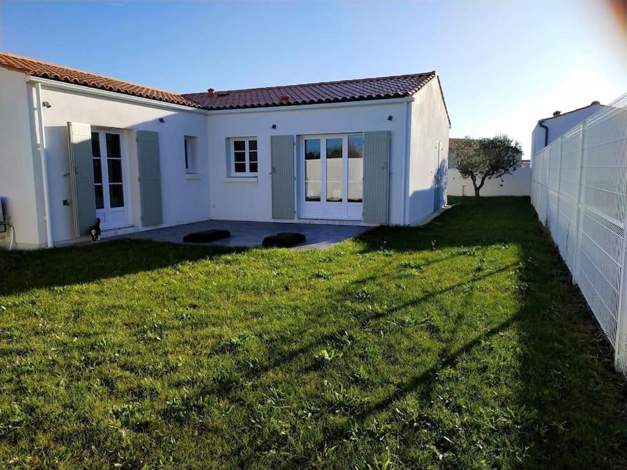 una pequeña casa blanca con un patio verde en Maison Moderne à Saint-Denis, en Saint-Denis-dʼOléron