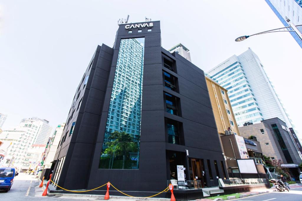 a black building with blue windows on a city street at CANVAS BLACK Guesthouse in Busan