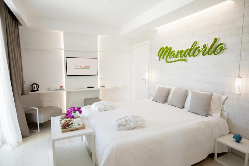 a white bedroom with a large bed with a sign on the wall at San Lorenzo Boutique Hotel & SPA in Polignano a Mare