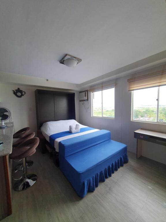 a bedroom with two beds and a table and windows at Amaia Steps Capitol Central N814 in Bacolod