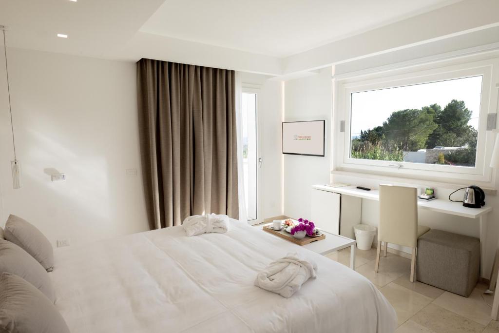 a white bedroom with a bed and a desk and a window at San Lorenzo Boutique Hotel & SPA in Polignano a Mare