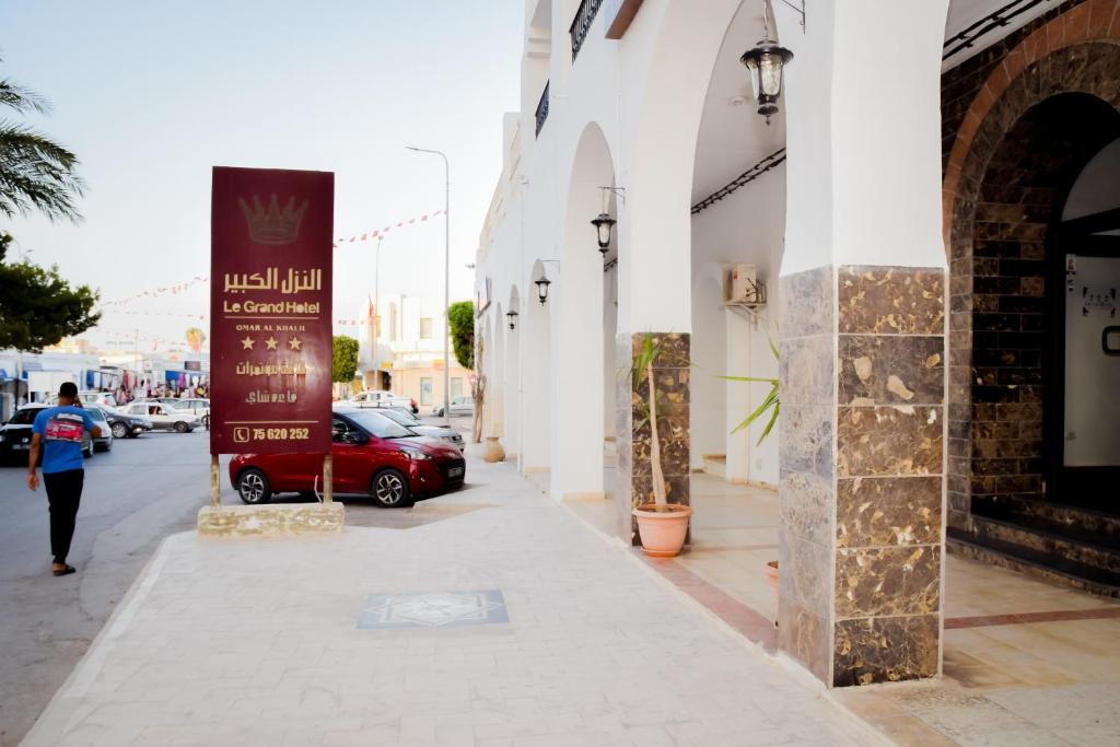 un'auto rossa parcheggiata in una strada accanto a un edificio di LE GRAND HOTEL a Houmt Souk