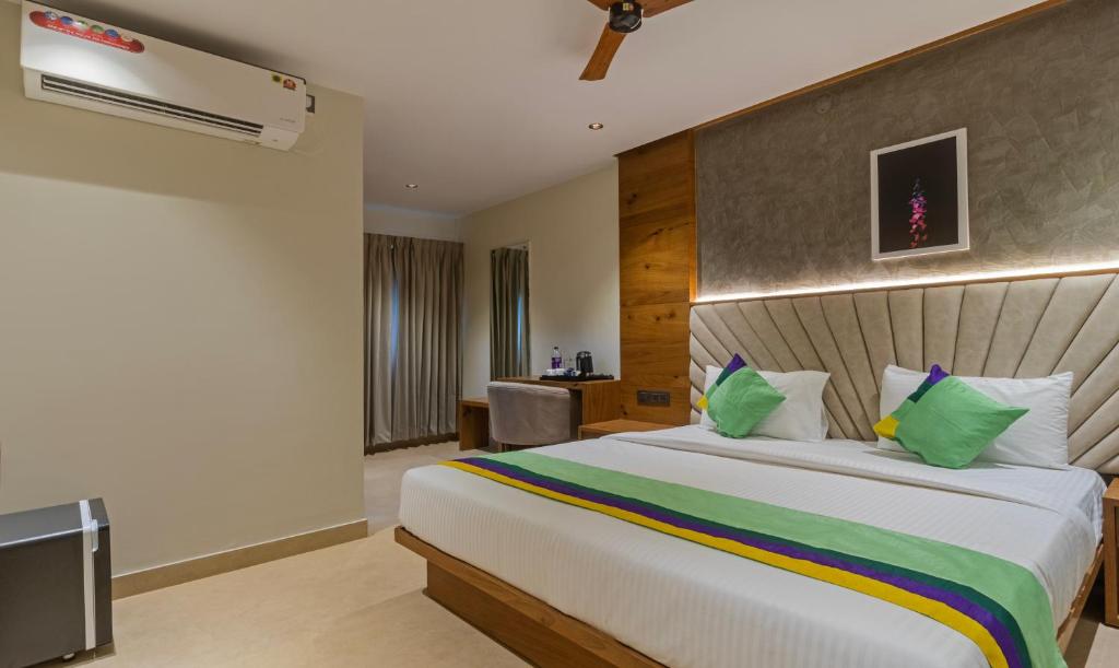 a bedroom with a large white bed with green pillows at Treebo Trend Tiba in Bangalore