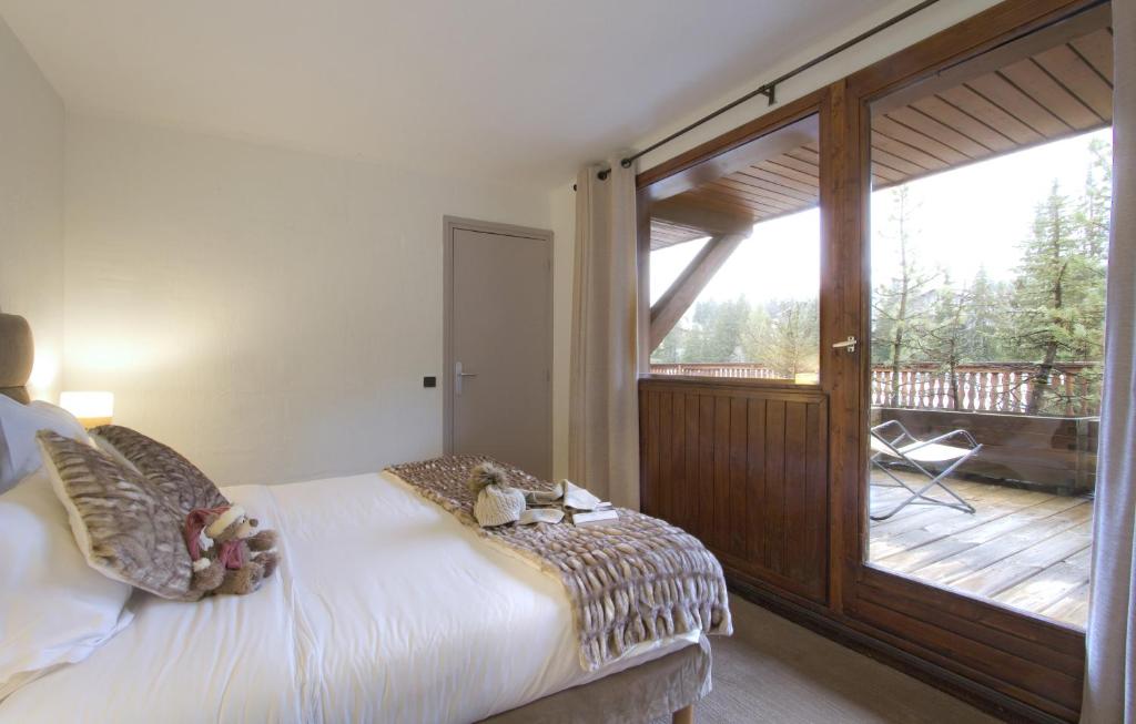 a bedroom with a bed and a balcony with a sliding glass door at Odalys Hotel New Solarium in Courchevel