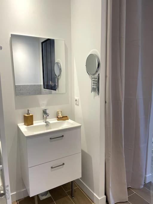 a white bathroom with a sink and a mirror at Bleu Suprême balnéo in Vierzon